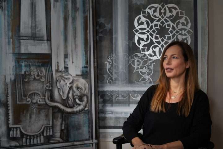 l'artista Irem Incedayi fotografata accanto ad un suo quadro