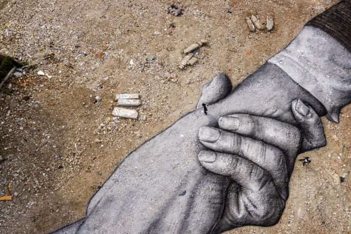 due mani dipinte dallo streetartist Saype in bianco e nero in una zona della Turchia sulle macerie del terremoto